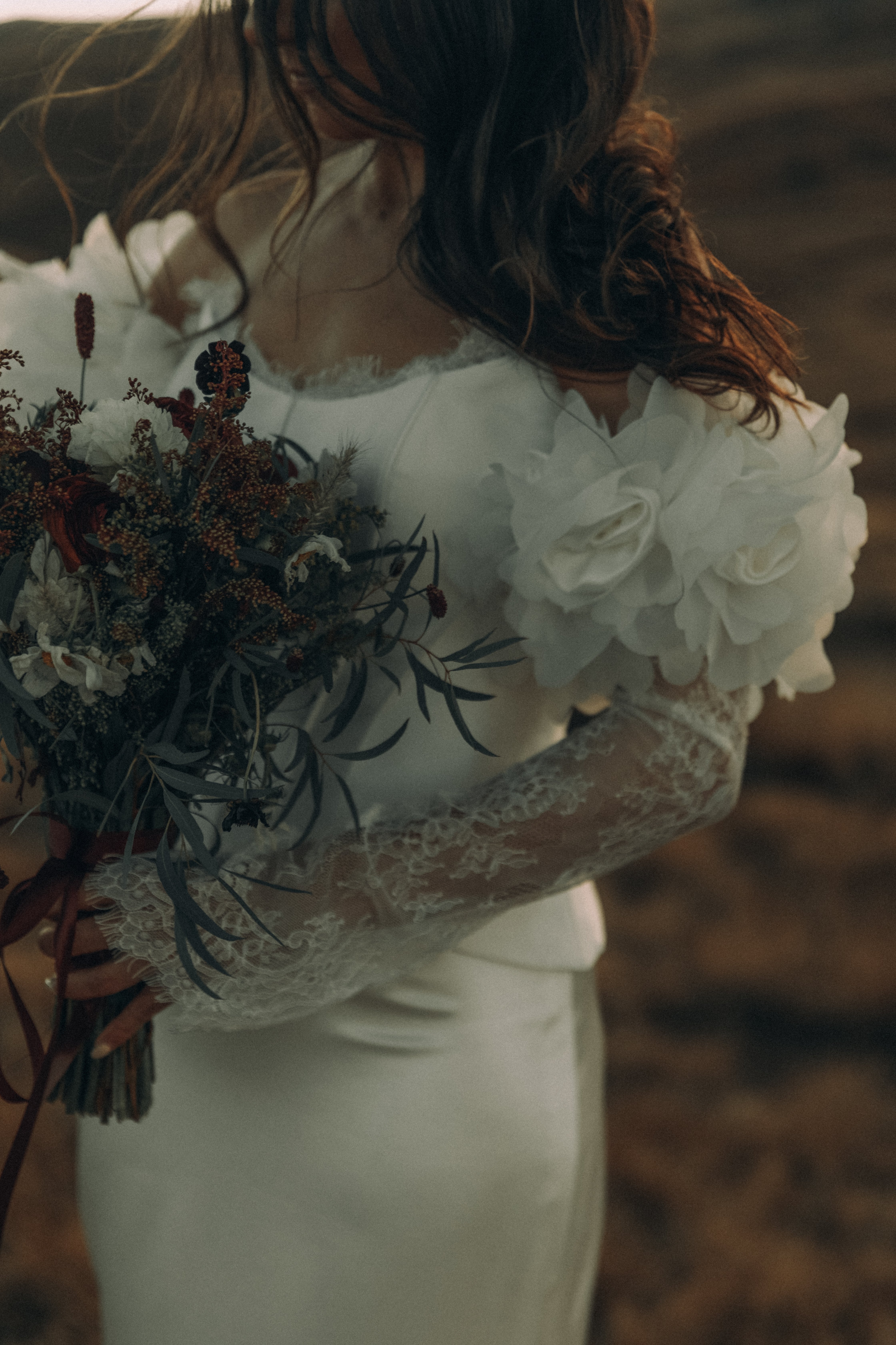 Bride in white dress with floral sleeves holding bouquet
